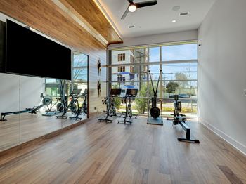 A home gym with a large window and a tv on the wall